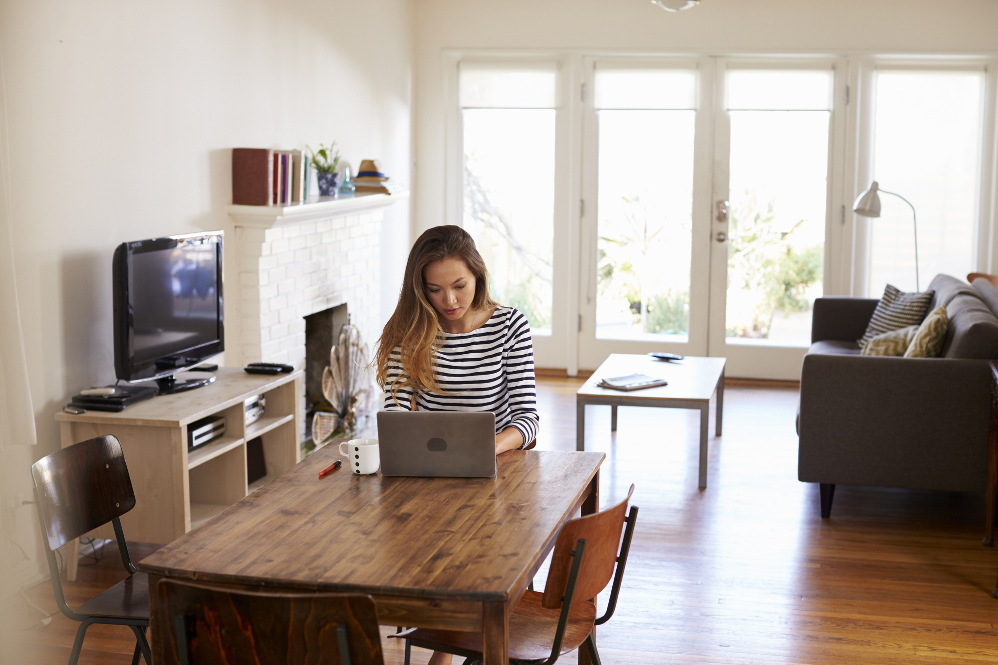 A person works remotely from their home in their dining area at the table.